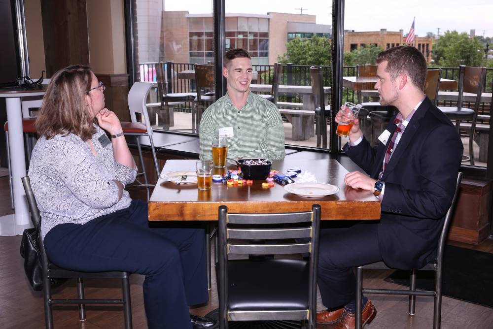 three people sitting at table drinking and talking